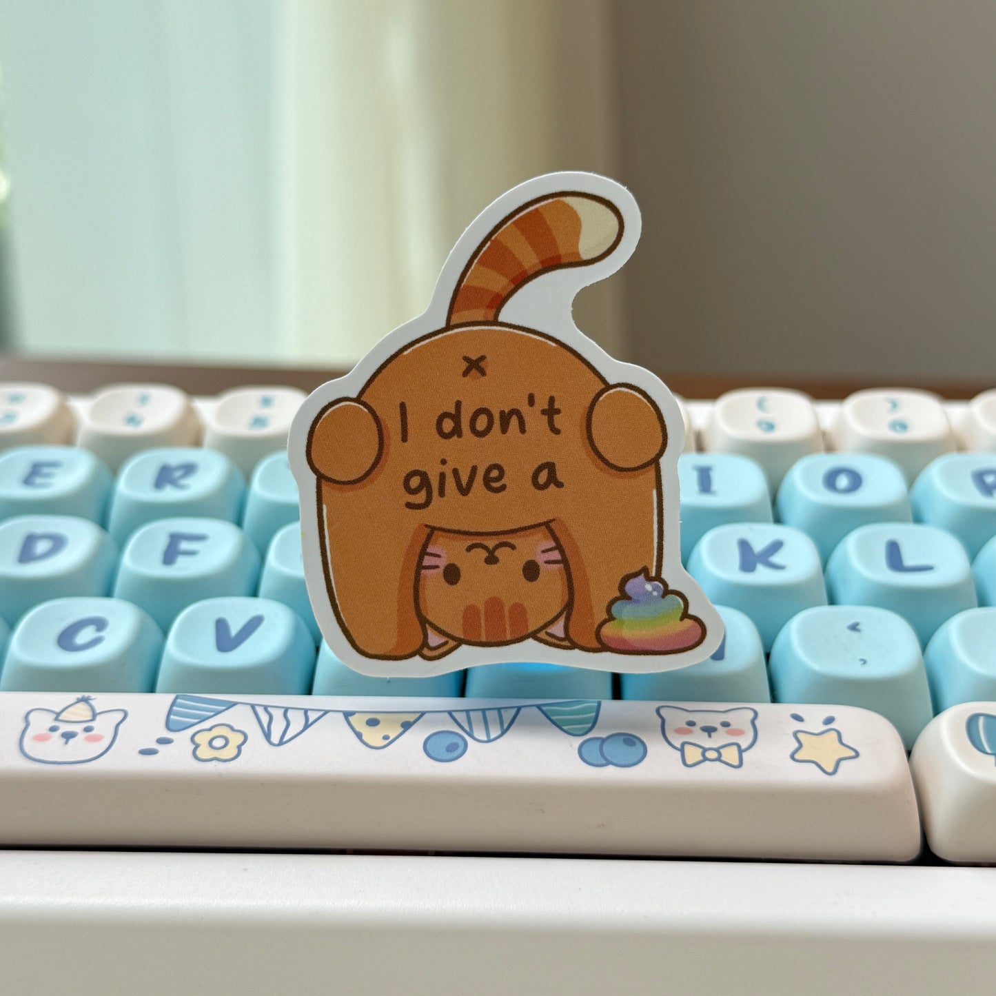 sticker of a cat with text of 'I don't give a shit' and rainbow poop