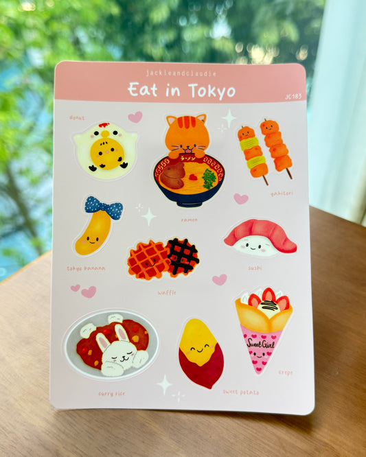 Sticker sheet titled 'Eat in Tokyo' with various food-themed illustrations on a wooden surface.