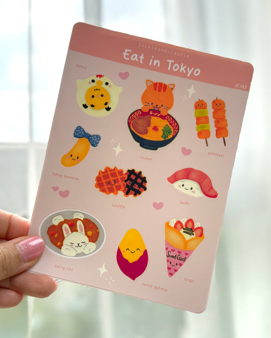 Sheet of decorative stickers with cartoon food illustrations held by a hand.