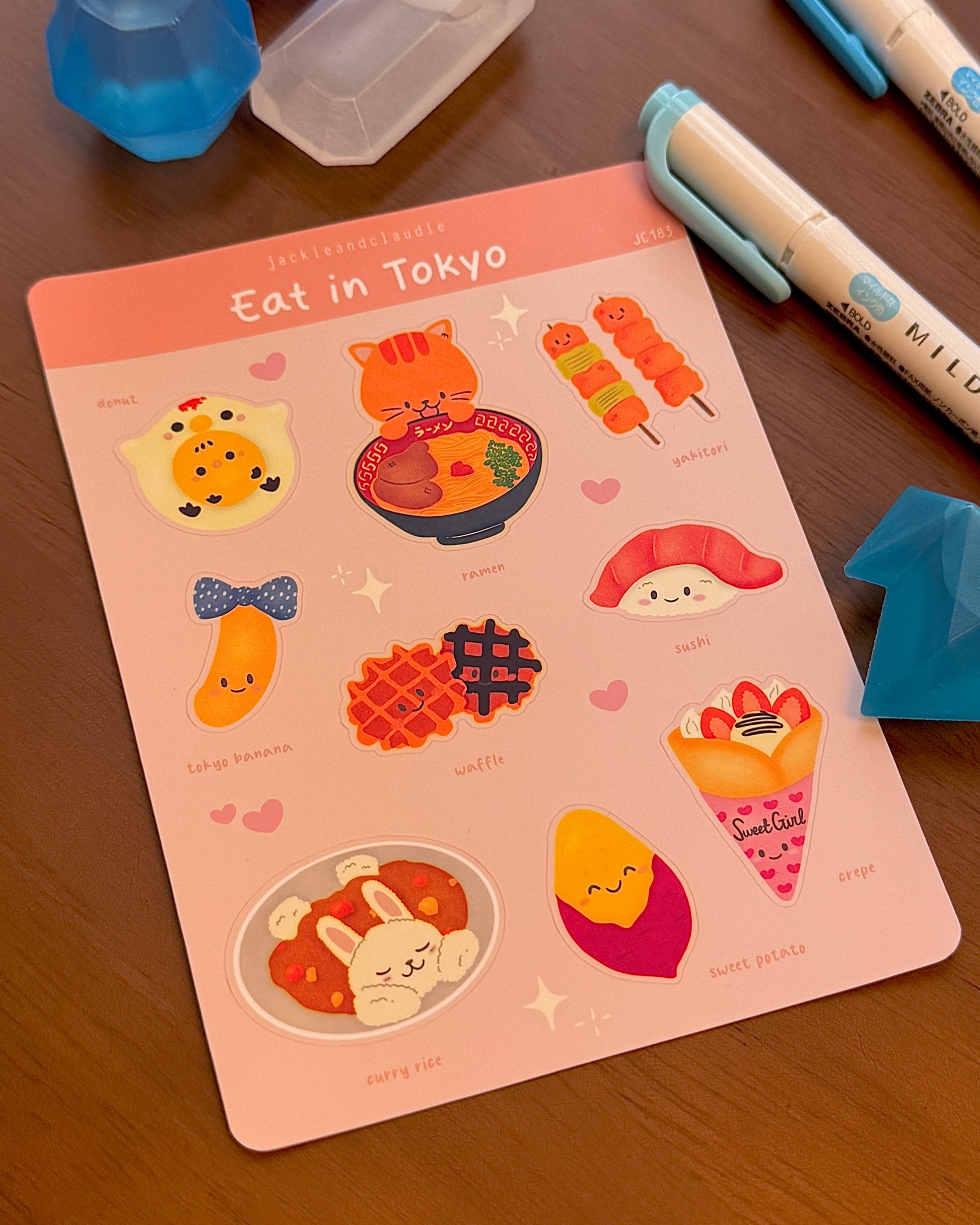 Sticker sheet titled 'Eat in Tokyo' with cute food illustrations on a wooden surface.