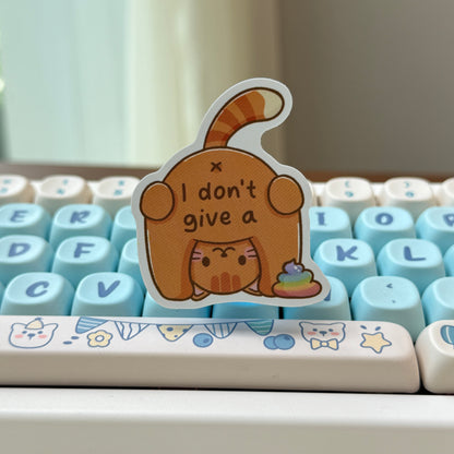 sticker of a cat with text of 'I don't give a shit' and rainbow poop