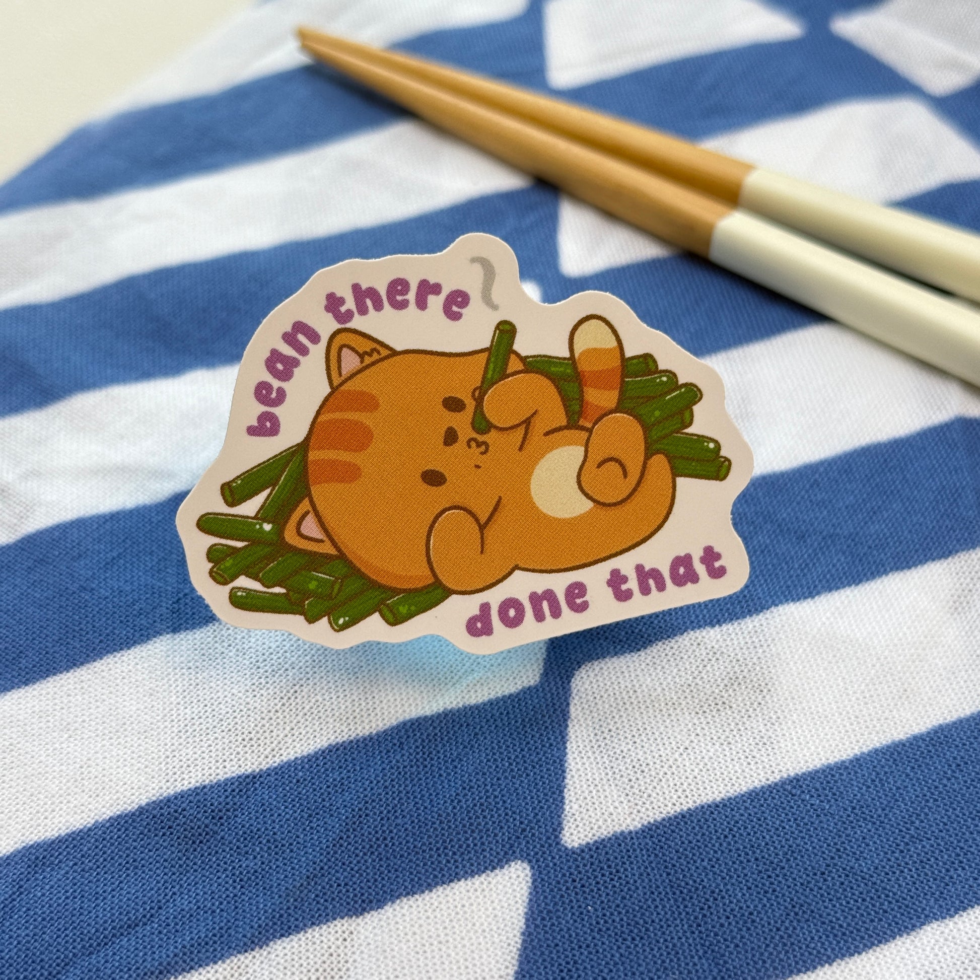 Sticker of a cat eating green beans with text 'bean there done that'