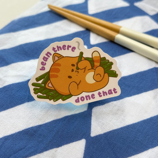 Sticker of a cat eating green beans with text 'bean there done that'